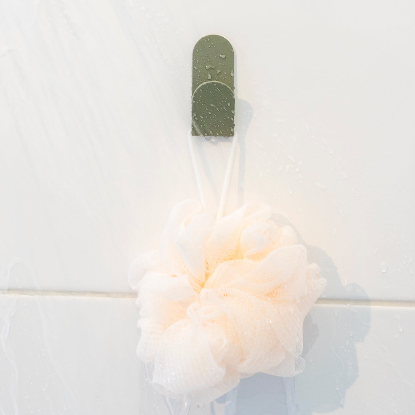patère vert de gris qui suspend une mousse de douche 